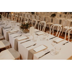 Trestle tables with white linen, accompanied by our white bentwood chairs